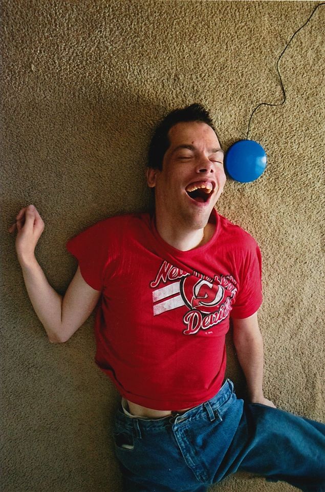 Joe Bassi, lying on the floor next to his computer switch and smiling for his brother Alexander.